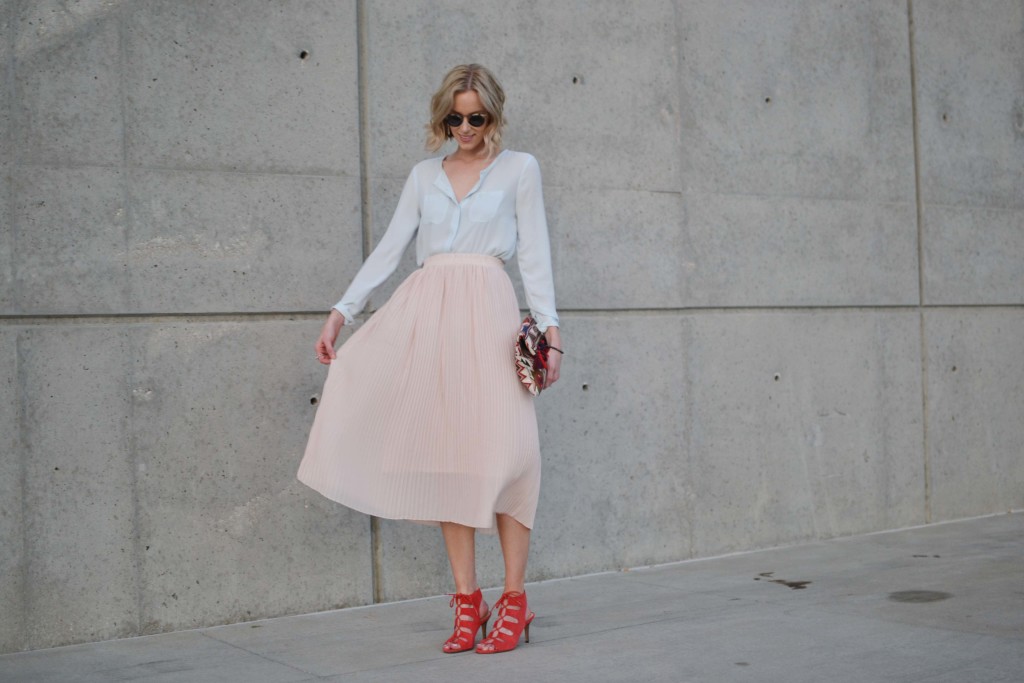 blush pleated midi skirt, pale blue blouse, red lace up heels, tassel clutch, krewe sunglasses