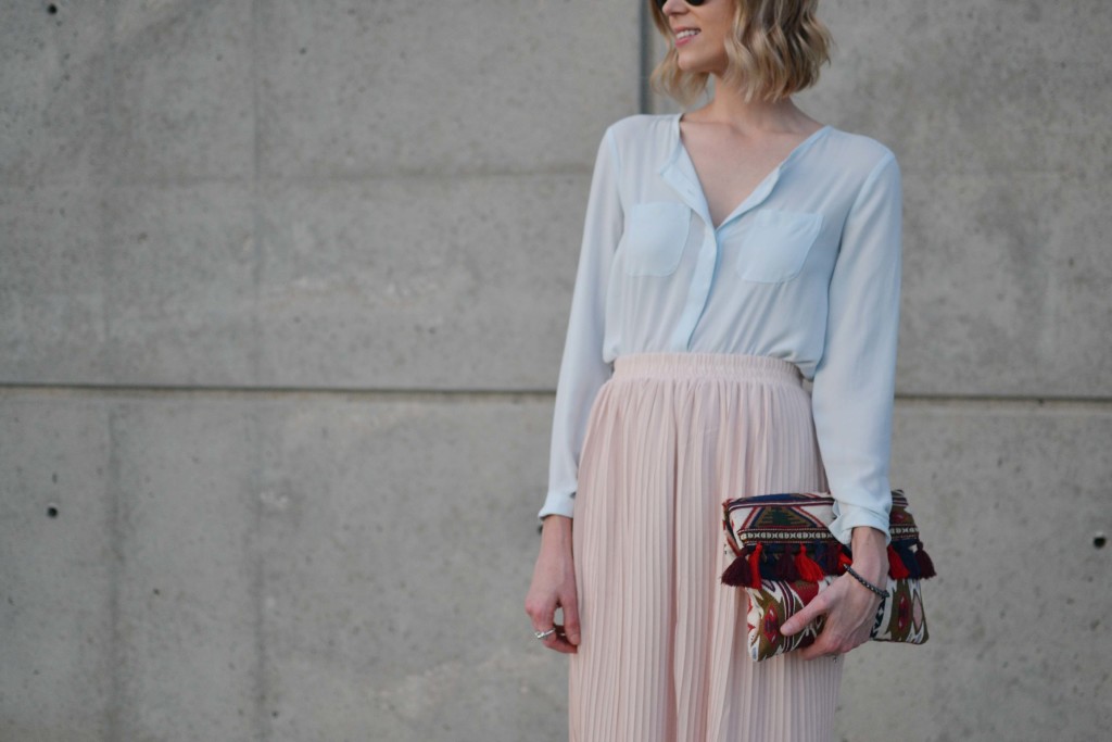blush pleated midi skirt, pale blue blouse, tassel clutch details