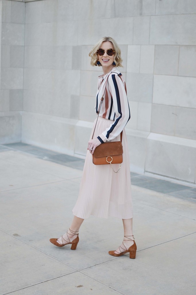This striped blouse and blush pleated midi skirt make for a stylish work outfit. 
