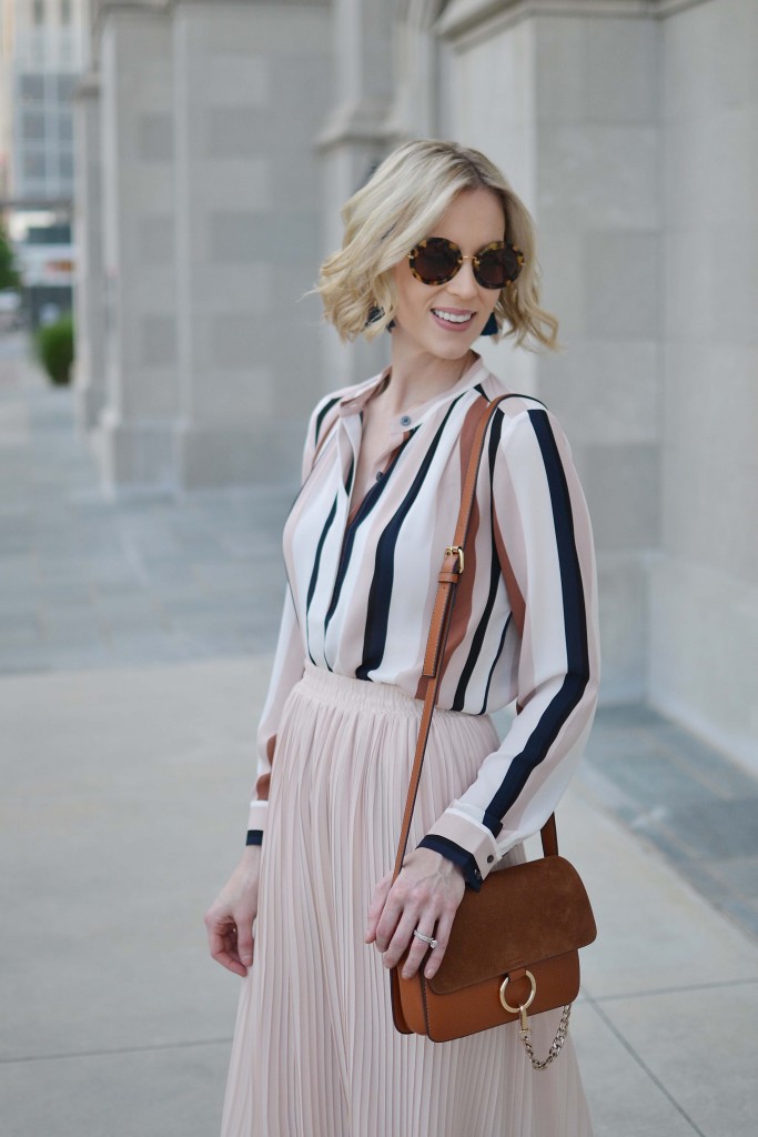This striped blouse and blush pleated midi skirt make for a stylish work outfit. 
