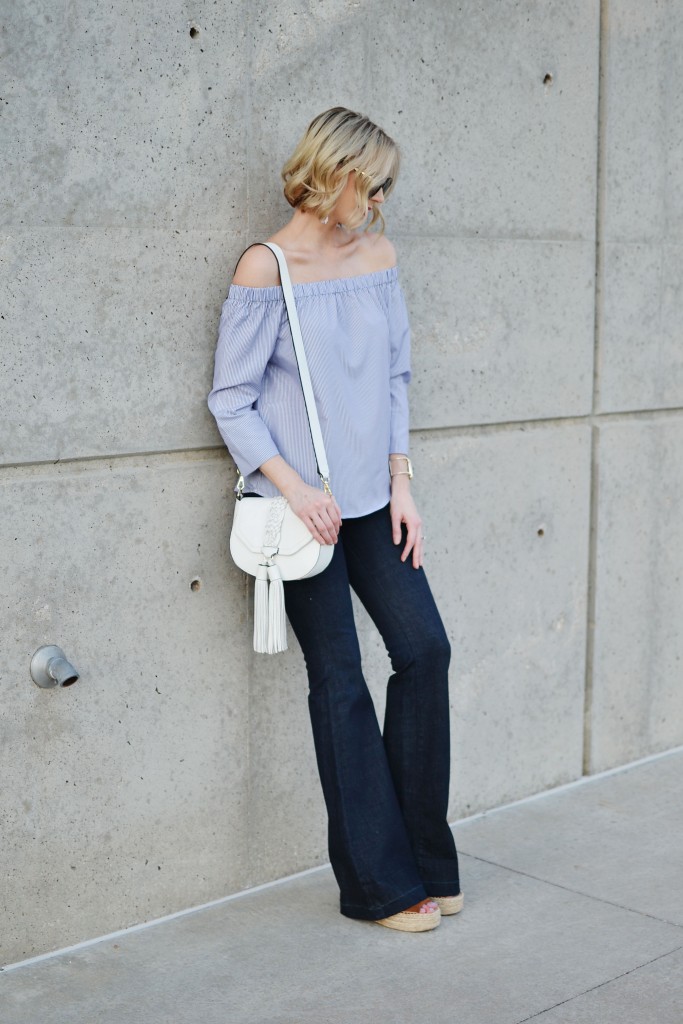 blue and white striped off the shoulder top, white tassel bag, flare jeans, wedges
