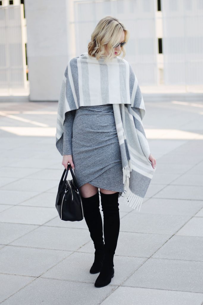 how to style a poncho with a dress, grey ruched dress with black over the knee boots and grey striped poncho draped over shoulders as wrap