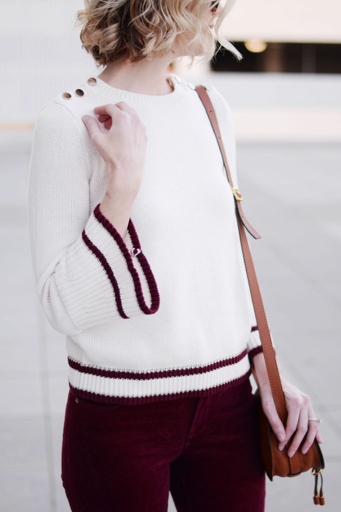 cream bell sleeve sweater with burgundy striped hem and gold shoulder button detail
