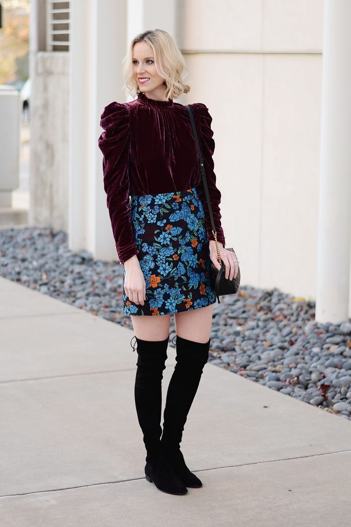 wine colored velvet top with puff sleeves, floral print skirt, and over the knee boots