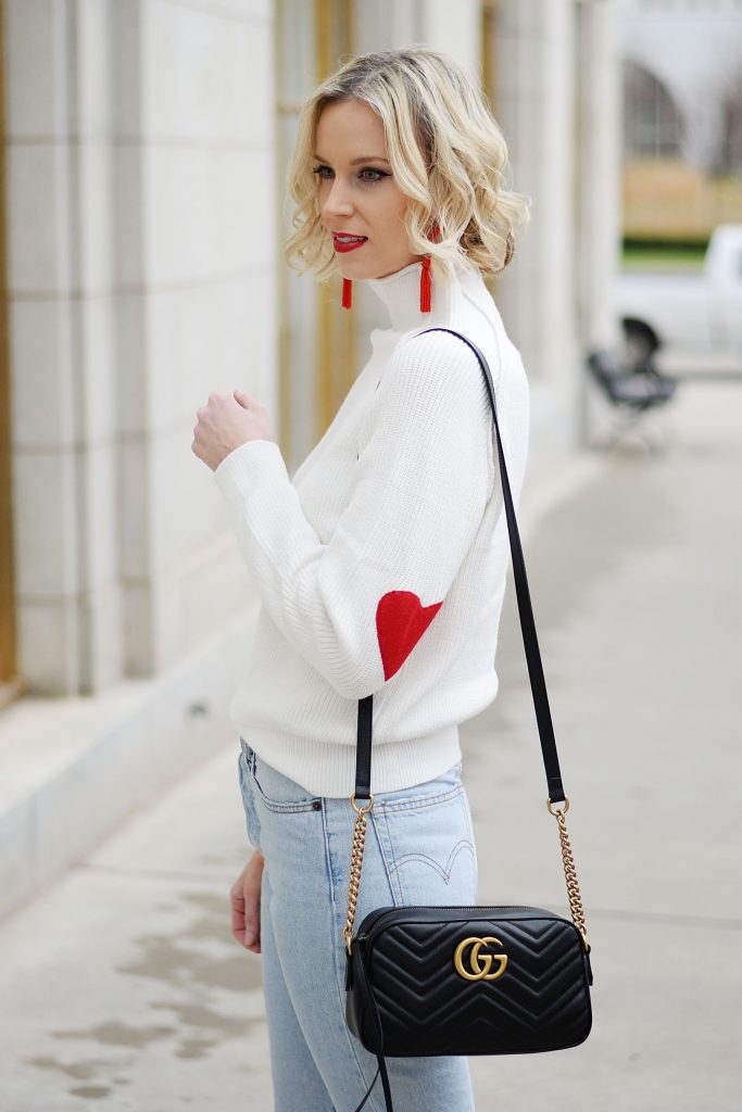 white sweater with red heart elbow patches and black gucci marmont bag