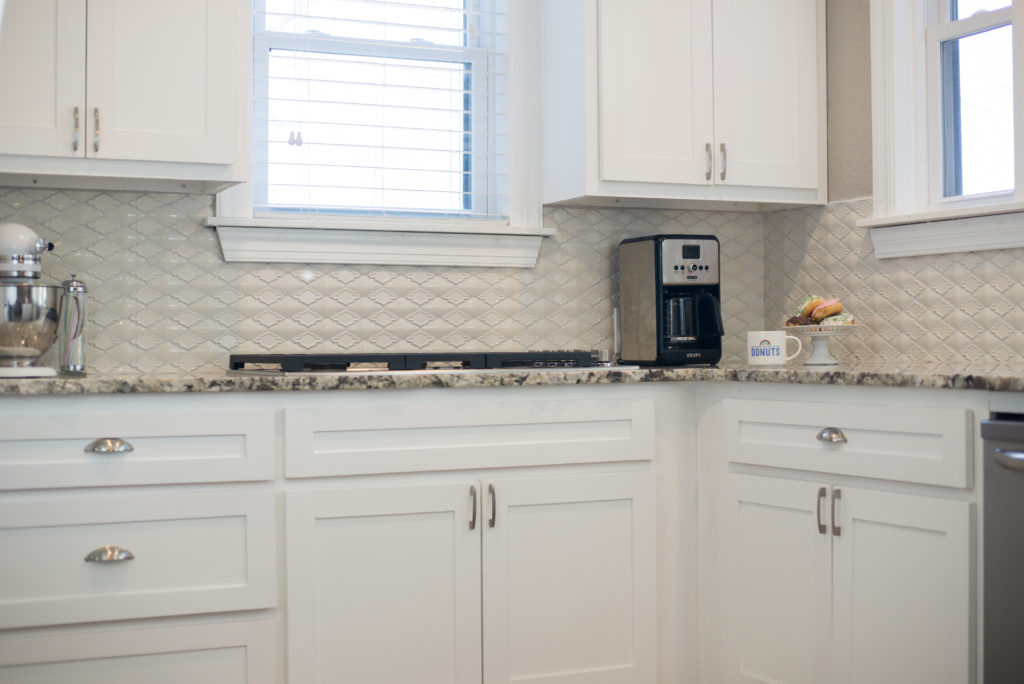 all white kitchen with patterned white tile backsplash 