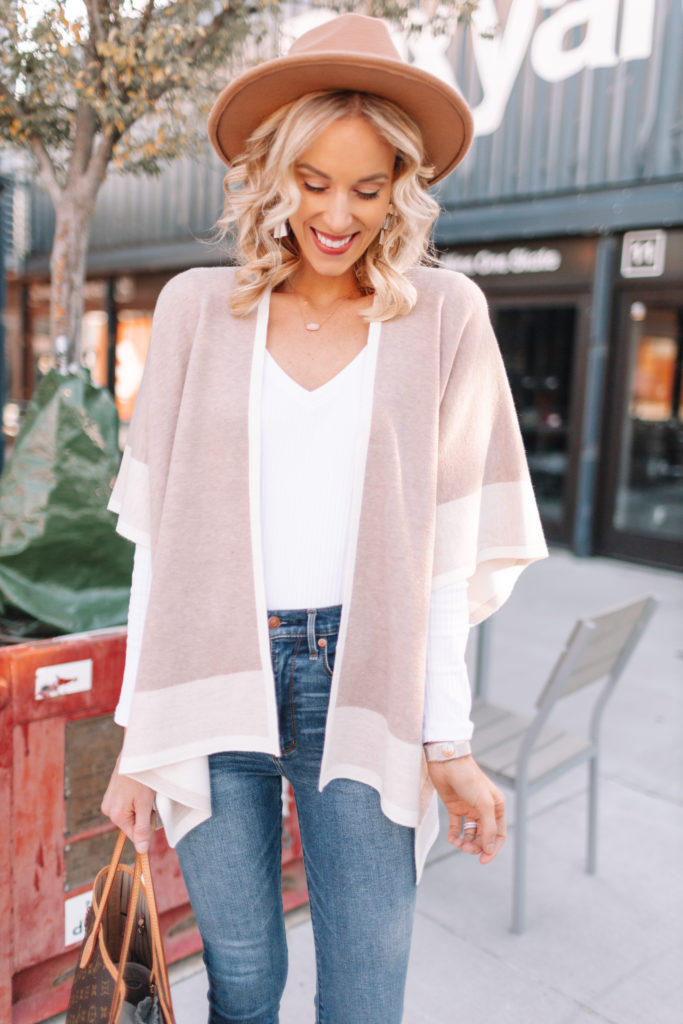 neutral poncho wrap for fall styled with white v-neck t-shirt and hat